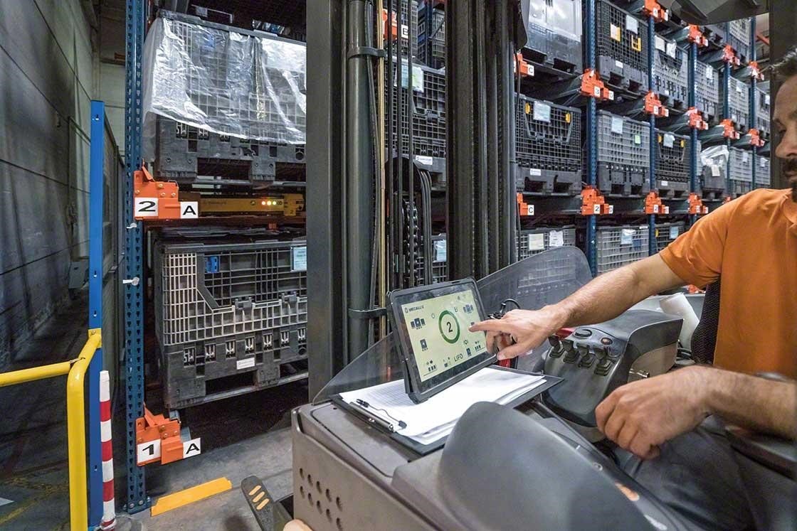 Ein Bediener steuert mit einem digitalen Tablet ein Pallet-Shuttle vom Gabelstapler aus Ein Bediener steuert mit einem digitalen Tablet ein Pallet-Shuttle vom Gabelstapler aus