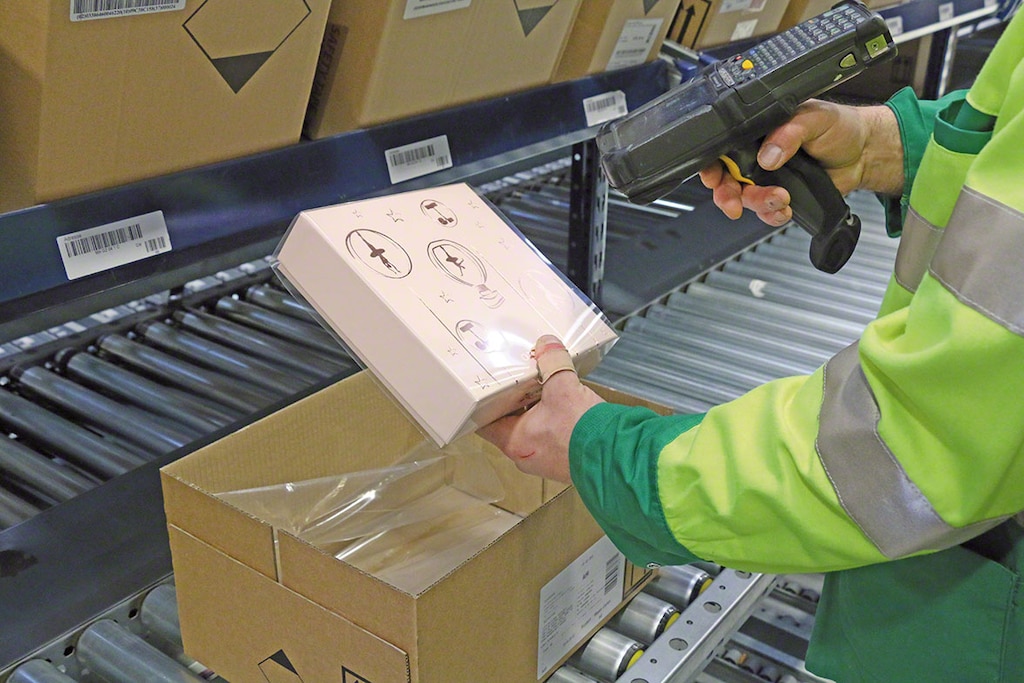 Kommissionierer, der einen Artikel mithilfe eines Handscanners entnimmt, der mit der Kommissioniersoftware verbunden ist. Kommissionierer, der einen Artikel mithilfe eines Handscanners entnimmt, der mit der Kommissioniersoftware verbunden ist.