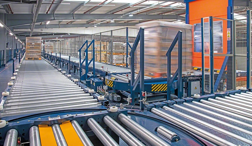  autonom zu transportieren. Diese Stapler sind für den Transport von Waren von einem Ort zum anderen konzipiert, ohne dass sie von einem Lagerarbeiter gefahren werden müssen. Automatisierte Gabelstapler sind mit modernster Technologie wie Sensoren, Navigationssystemen und Kameras für den autonomen Betrieb ausgestattet. Der Gabelstapler kann außerdem dank einer Steuerungssoftware: sich sicher in der Umgebung bewegen und dabei Hindernissen und Menschen ausweichen. Lasten mit Präzision aufnehmen und ablegen. bestimmte Aufgaben ausführen, wie z. B. das Be- und Entladen von Paletten aus Regalen. Routen optimieren, um die internen Transportzeiten zu minimieren. mit anderen Teams und Systemen innerhalb der Anlage kommunizieren, um die Abläufe zu koordinieren. Automatisierte Gabelstapler eignen sich besonders für Lager, in denen große Mengen an Waren umgeschlagen werden oder die ein hohes Maß an Zuverlässigkeit bei der Handhabung von Produkten erfordern. Arten von automatisierten Gabelstaplern und Beispiele in der Industrie Es gibt verschiedene Arten von automatisierten Gabelstaplern auf dem Markt, die für alle möglichen Anwendungen in der Industrie und Logistik ausgelegt sind. Die gängigsten Arten sind: Fahrerlose Transportfahrzeuge (FTF) FTF sind Transportmaschinen, die sich autonom und ohne Fahrer bewegen. Sie ähneln den manuellen Gabelstaplern, aber der grundlegende Unterschied besteht darin, dass sie einem vordefinierten Kreislauf folgen, der ihre Bewegung steuert. FTF können zwei Führungssysteme verwenden: Die Laserführung, bei der ein Laser zur Erkennung von Markierungen auf dem Boden eingesetzt wird, und die Drahtführung, bei der ein im Boden vergrabener Draht verwendet wird. FTF verbinden automatisch verschiedene Bereiche innerhalb eines Lagers oder bestimmte Lagerbereiche mit Produktionslinien. Ein Beispiel für den Einsatz von FTF in der Industrie ist Novartis, ein multinationales Pharma- und Biotech-Unternehmen. Das Unternehmen setzt diesen Fahrzeugtyp in seinem von Mecalux in Polen gebauten Hochregallager für den effizienten Versand von Waren an die Produktion ein. „Diese Gabelstapler ermöglichen es uns, über vollständig freie Räume und Verkehrsgänge zu verfügen“, bestätigt Tomasz Marchewa, Leiter der Lieferkette des Unternehmens. FTF verbinden das Lager und die Produktionsstätte von Novartis völlig selbstständig AMR Autonome mobile Roboter (AMR) können Aufgaben ausführen und sich im Lager bewegen, ohne von jemandem gesteuert zu werden. Zu diesem Zweck sind sie mit Sensoren, einer Navigationssoftware und digitalen Plänen des Lagers ausgestattet, um ihre Umgebung wahrzunehmen. Sie haben die gleiche Funktion wie FTF: Transport der Ware zwischen zwei Punkten. Der Unterschied zwischen den beiden liegt jedoch in ihrem Navigationssystem. Während sich FTF unter Befolgung einer vordefinierten Route bewegen, die sie durch laser- oder drahtgesteuerte Systeme erkennen, passen die AMR ihre Strecke gemäß den Informationen an, die sie in Echtzeit erhalten, und zwar ohne Verwendung von Führungsschienen, Kabeln oder Magnetstreifen. Mit AMR in Lagern wird die Produktivität gesteigert. Das spanische Notbeleuchtungsunternehmen Normagrup hat mit dieser Lösung den Umschlag von Rohstoffen optimiert: Vier autonome mobile Roboter befördern die Waren aus dem automatisierten Behälterlager zu den Produktionslinien. Nach Beendigung der Montage eines Sets wird es von einem Fahrzeug abgeholt und so schnell wie möglich zu der entsprechenden Produktionslinie gebracht. „Angesichts des immer hektischeren Produktionstempos mussten wir dringend die Handhabung dieser Waren optimieren und richtig organisieren“, berichten Verantwortliche bei der Normagrup. Die AMR im Lager von Normagrup sorgen für eine flexible und sichere Bewegung der Waren Andere automatische Handhabungsgeräte Abgesehen von automatisierten Gabelstaplern gibt es auf dem Logistikmarkt auch andere robotergestützte Transportlösungen, die den internen Warenverkehr rationalisieren: Lagerroboter In dieser Kategorie zeichnen sich automatische Lagergeräte wie Regalbediengeräte für Paletten und Behälter (Miniload) durch ihre Kapazität und Flexibilität beim Ein- und Auslagern von Waren aus den Regalen aus. Es gibt verschiedene Arten von Regalbediengeräten: von einmastigen über zweimastige bis hin zu automatischen Dreiseitenstaplern. Zahlreiche Unternehmen setzen auf Lagerroboter, um den Warentransport in ihren Lagern zu automatisieren und die herkömmlichen Gabelstapler zu ersetzen. Diese Roboter bewegen sich in den Lagergängen auf und ab und orten mithilfe von Sensoren und Kameras die Produkte, die sie aus den Regalen entnehmen. So nutzte z. B. der französische Papierhersteller Clairefontaine diese Technologie, um die Lagerhaltung in seiner Logistikanlage im Elsass, Frankreich, zu verbessern: „Durch die Automatisierung unseres Logistikzentrums haben wir die Leistung und die Reaktionsschnelligkeit verbessert und zudem die Betriebskosten und bei der manuellen Abwicklung auftretende Fehler verringert“, erklärt Florian Challe, Leiter der Logistikaktivitäten bei Clairefontaine. Clairefontaine hat die Produktivität seiner Logistik mit dem automatischen Pallet-Shuttle-System erhöht Transportroboter Automatisierte Förderanlagen wie Paletten- oder Behälterfördersysteme, sind effektive Lösungen, die die Warenbewegung im Lager erleichtern. Mit diesen automatisierten Fördersystemen lassen sich vielfältige Kreisläufe aufbauen, die die einzelnen Bereiche der Anlage miteinander verbinden. Ein weiteres Transportsystem, mit dem verschiedene Bereiche des Lagers miteinander verbunden werden können, sind schienengeführte Fördersysteme. Hierbei handelt es sich um automatische, durch einen Elektromotor angetriebene Wagen, die sich über eine vom Dach hängende oder auf dem Boden installierte elektrische Schiene bewegen. Im Logistikkomplex von ALPLA in Golborne (Vereinigtes Königreich) sparen Transportroboter z. B. Zeit und erhöhen die Effizienz bei sich wiederholenden Bewegungen von Lasten. Der Weltmarktführer in der Entwicklung und Herstellung von Kunststoffverpackungssystemen hat den Warenverkehr durch einen Kreislauf automatischer Förderbänder von Mecalux automatisiert, der das Lager mit den Produktionslinien verbindet. „Dank der installierten automatisierten Förderlösung haben wir Kosten und CO2-Emissionen gesenkt und können nun rund 2.500 Paletten pro Tag rund um die Uhr an sieben Tagen in der Woche transportieren“, sagt Liam Grimwood, technischer Leiter im ALPLA-Werk im Vereinigten Königreich. ALPLA hat den Warentransport zwischen Produktion und Lager mit einem Förderkreislauf optimiert 