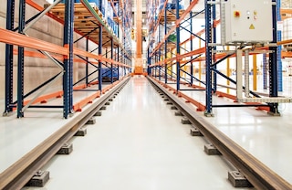 Das Dreiseitige Regalbediengerät bewegt sich auf inneren Schienen entlang des Ganges