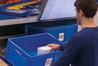 Der Lagermitarbeiter legt die Artikel in die jeweiligen Behälter auf der unteren Ebene der Hochleistungs-Kommissionierstation