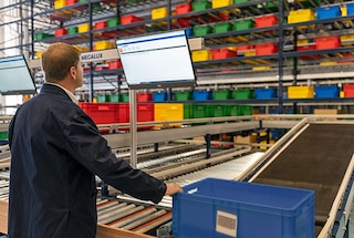 Die Behälter werden über Fördersysteme zur Kommissionierstation transportiert